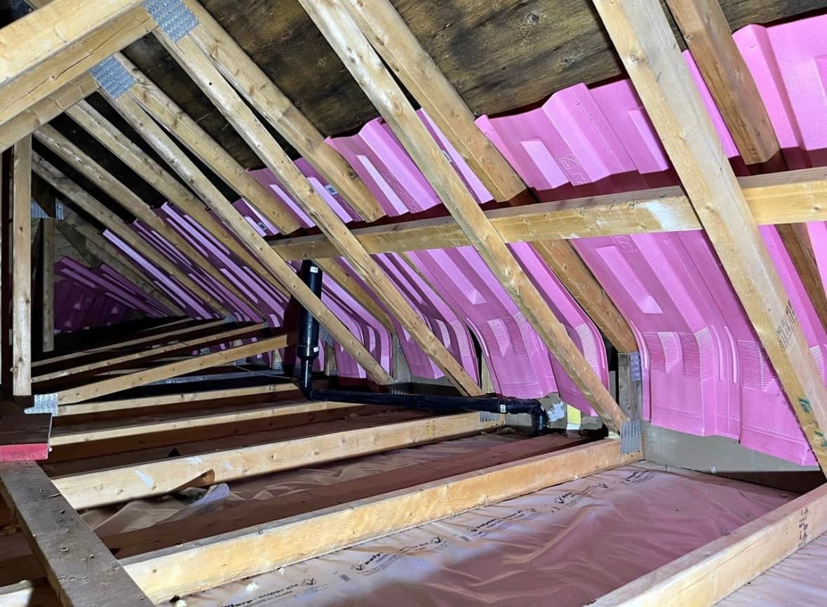 Pink rigid foam insulation panels installed between attic rafters